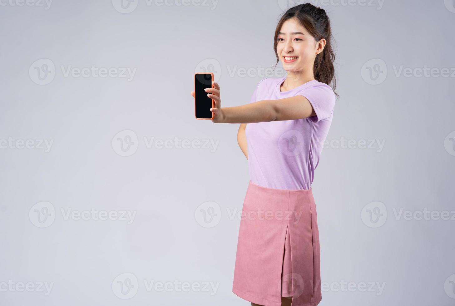 junge asiatische frau, die den leeren bildschirm des smartphones zeigt foto