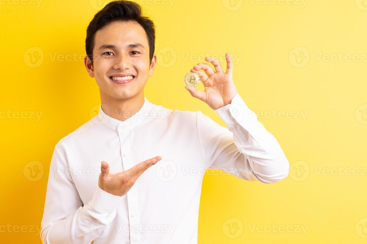 Asiatischer Geschäftsmann, der Bitcoin in der Hand hält, wite glückliches Gesicht foto