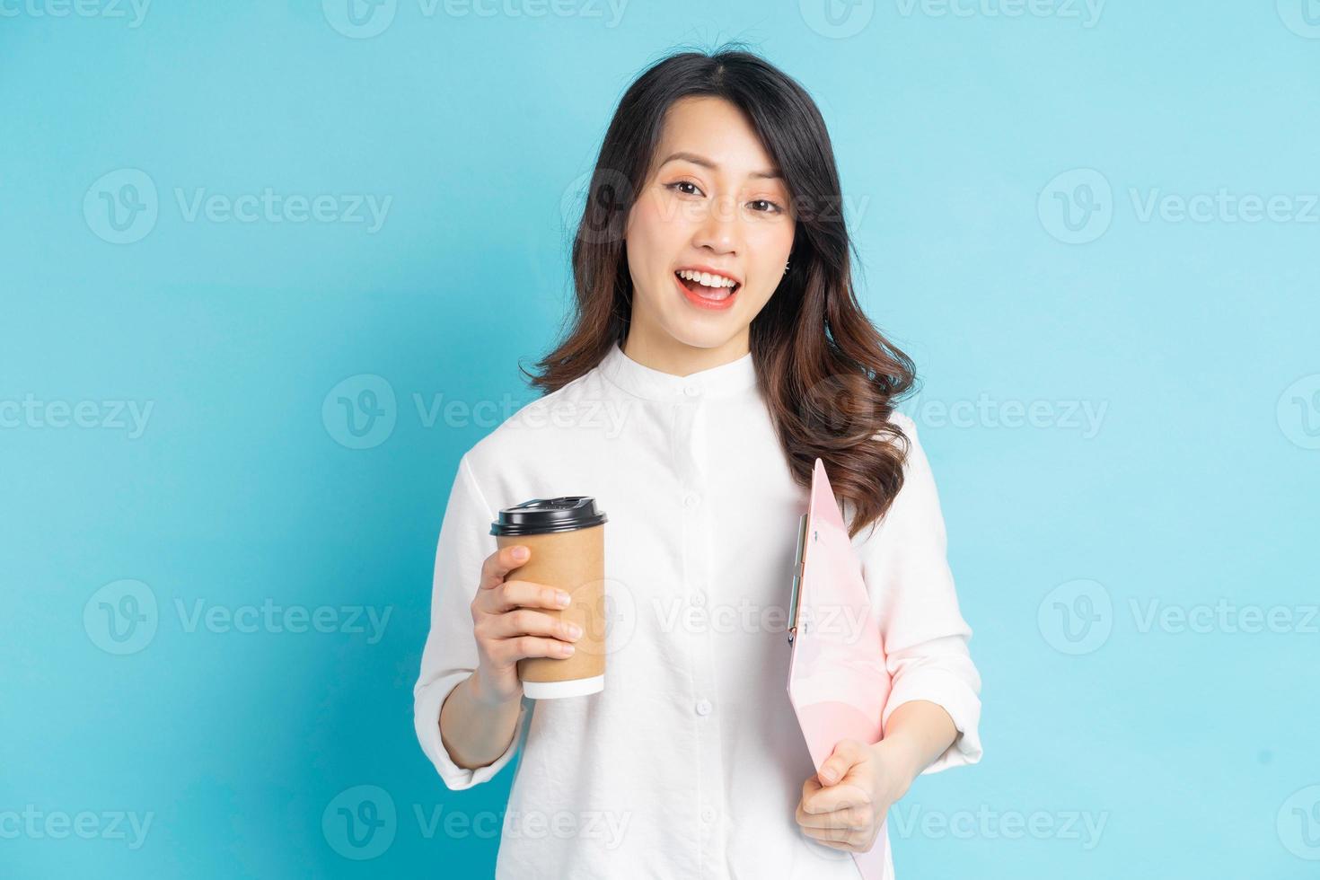 schöne asiatische geschäftsfrau, die papierkaffeetasse und broschüre in der hand hält foto