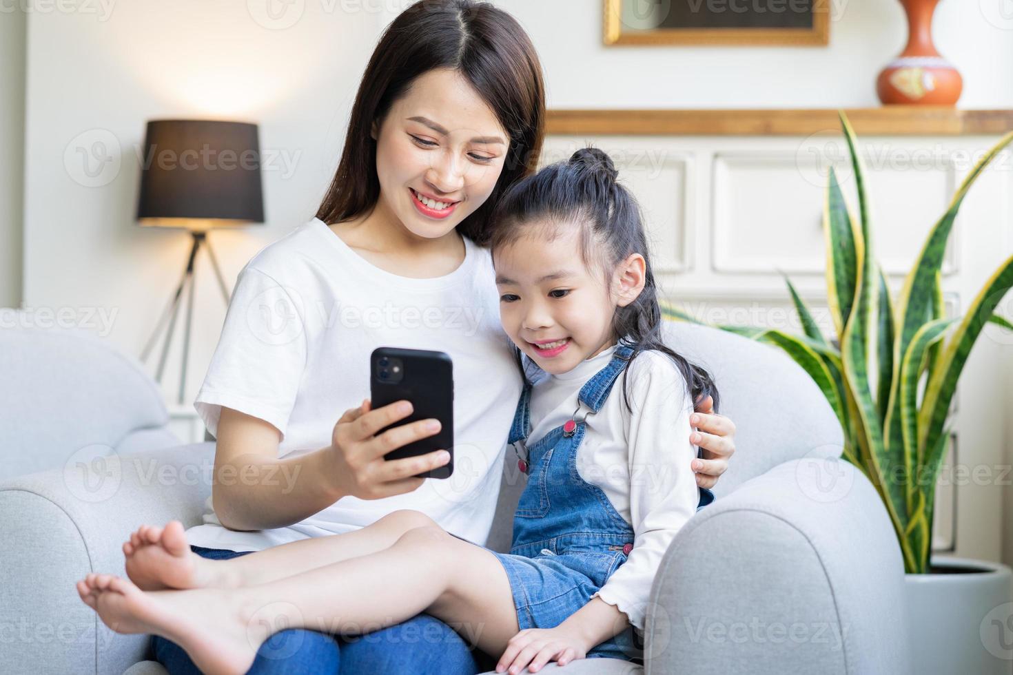 Mutter und Tochter schauen sich zu Hause gemeinsam Videos am Telefon an foto