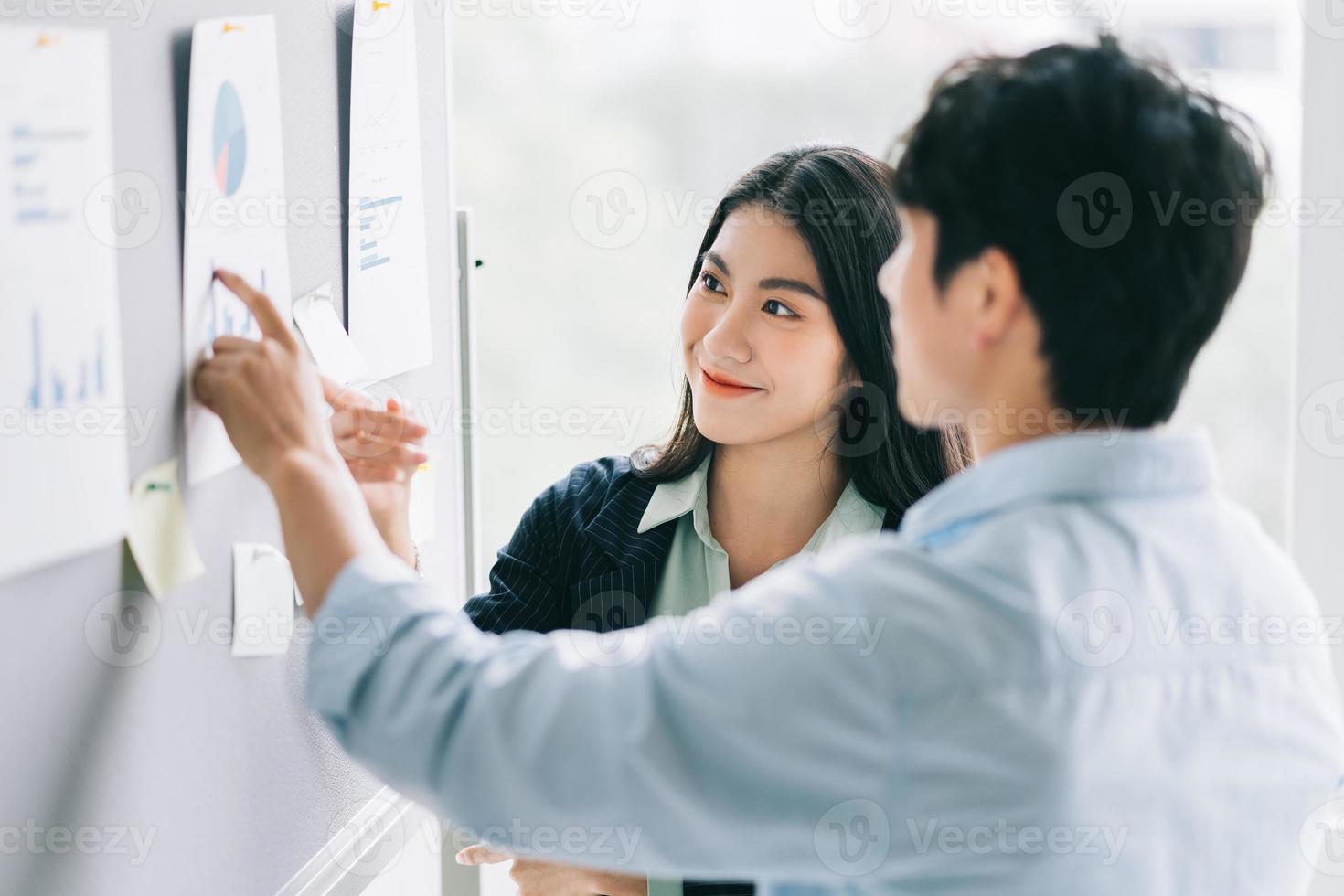 zwei junge asiatische geschäftsleute diskutieren anstehende pläne foto