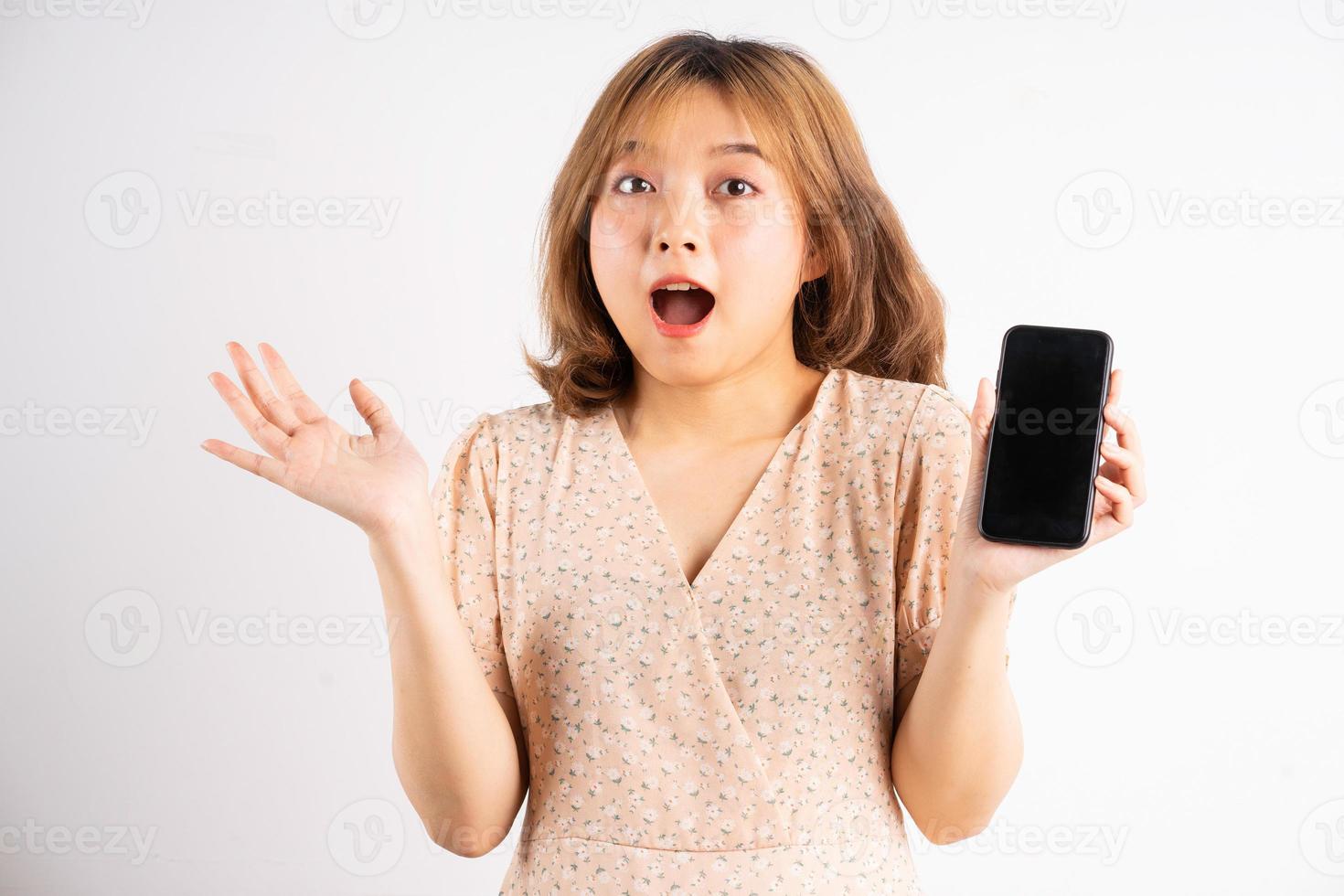 junges asiatisches mädchen, das telefon mit ausdrücken, gesten im hintergrund hält foto