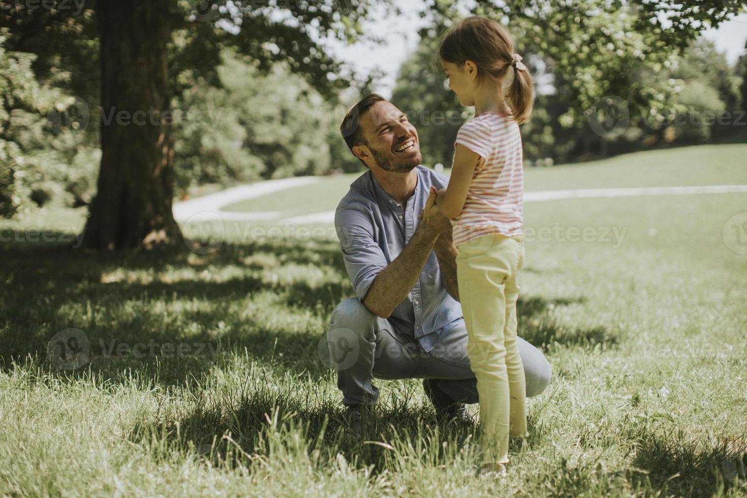 Vater mit Tochter, die Spaß auf dem Gras im Park hat foto