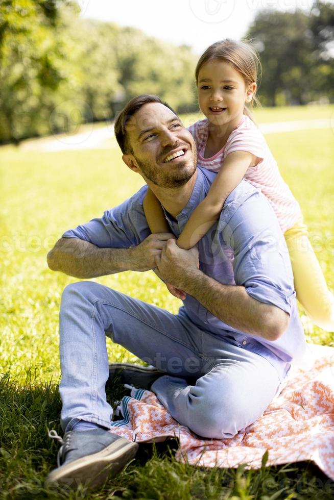 Vater mit Tochter, die Spaß auf dem Gras im Park hat foto