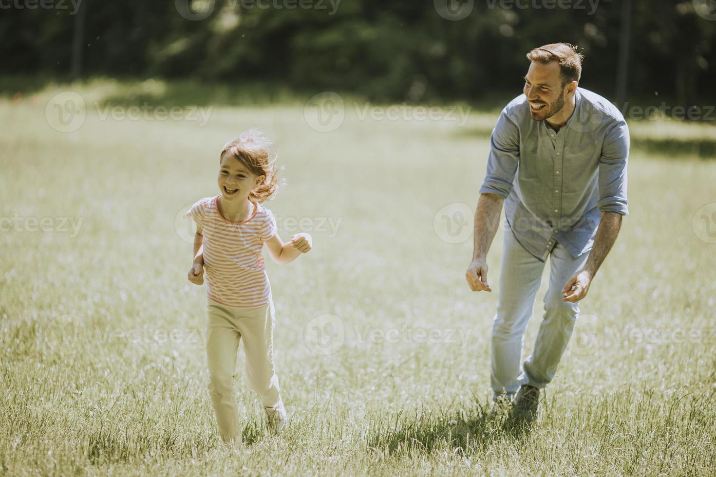 Vater jagt seine kleine Tochter beim Spielen im Park foto