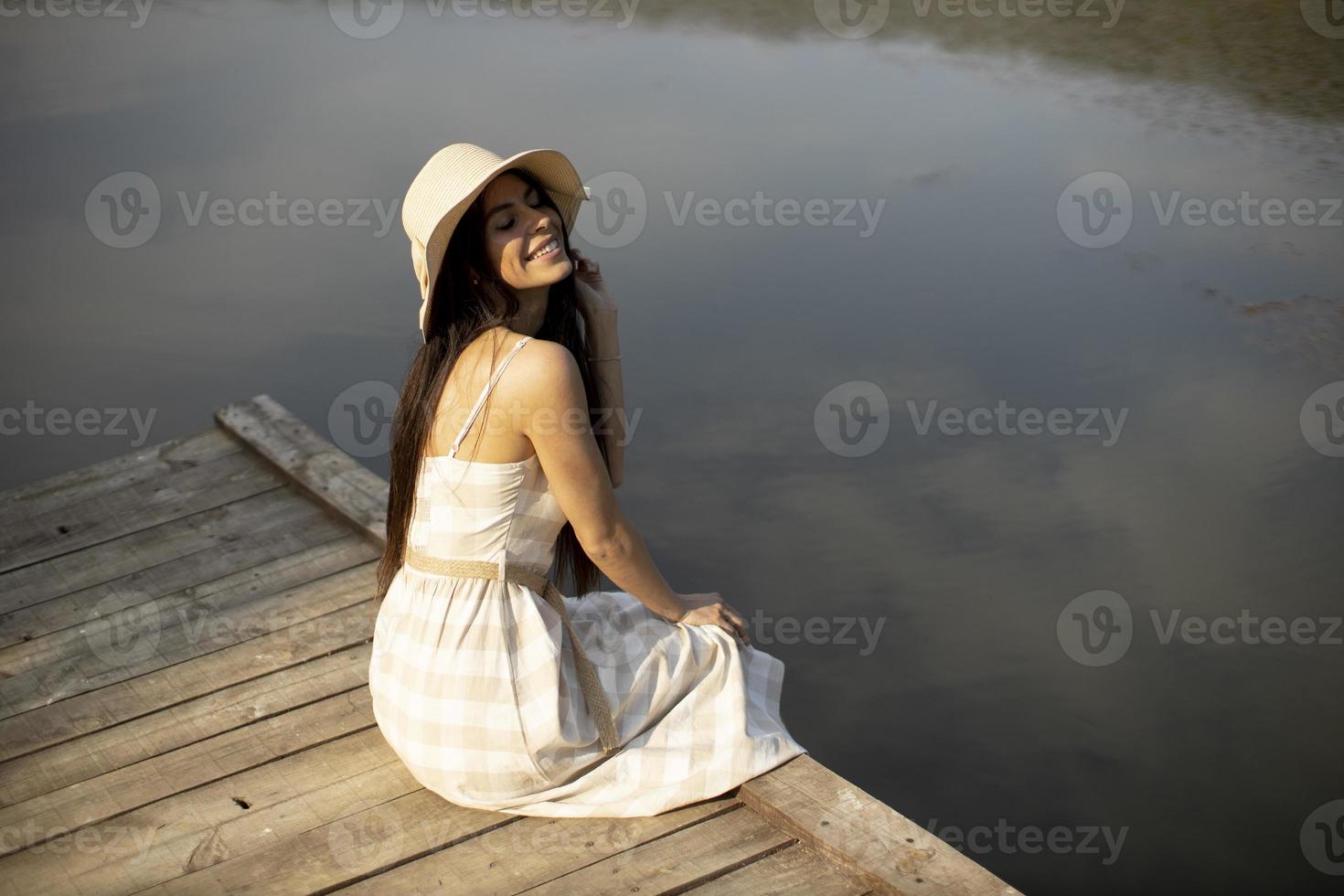 entspannende junge Frau auf Holzsteg am See foto