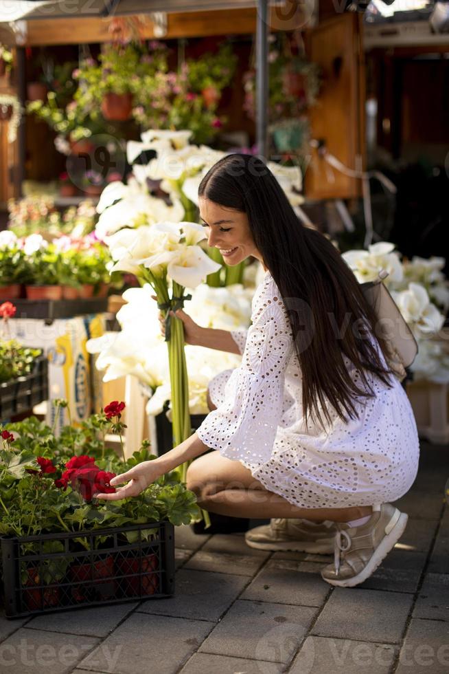 junge Frau kauft Blumen auf dem Blumenmarkt foto