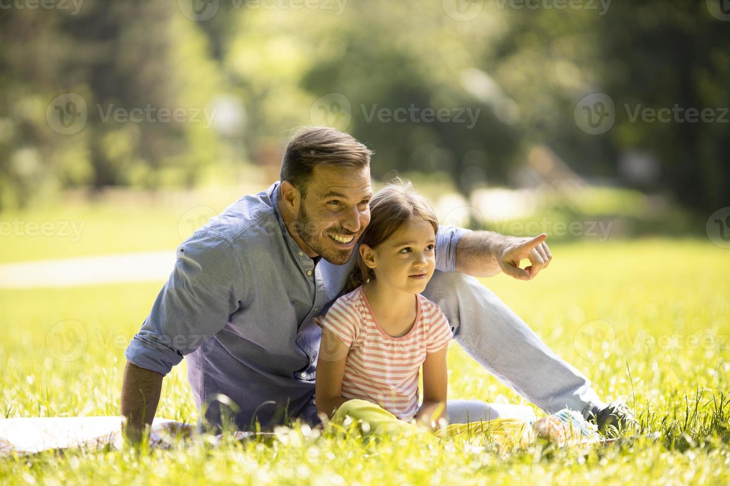 Vater mit Tochter, die Spaß auf dem Gras im Park hat foto