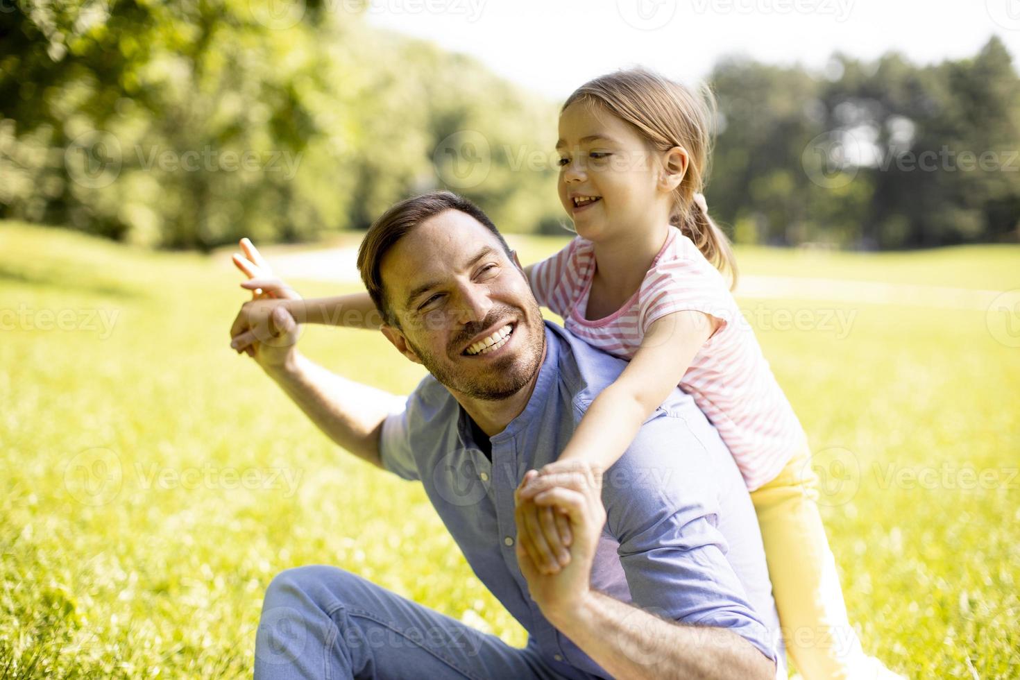 Vater mit Tochter, die Spaß auf dem Gras im Park hat foto