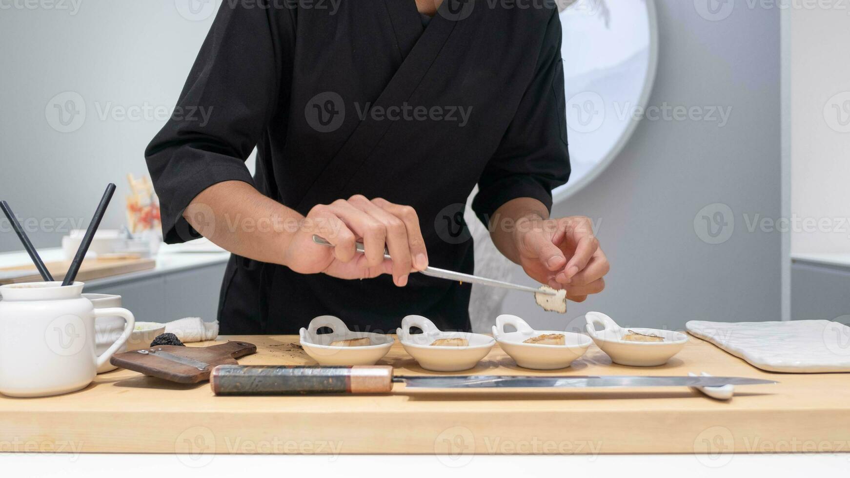 Fachmann Koch vorbereiten und Kochen roh frisch Fisch Zutat auf das Tabelle mit Messer zum köstlich Sushi und Sashimi Mahlzeit, Person Herstellung Luxus Omakase fein Essen japanisch Essen Restaurant Abendessen foto