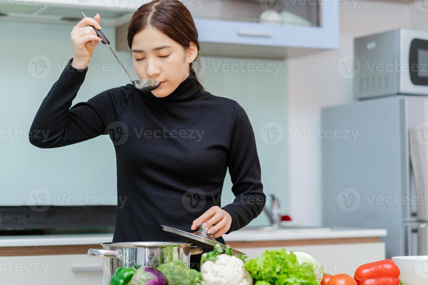 Frau probiert die Suppe, die sie kocht foto