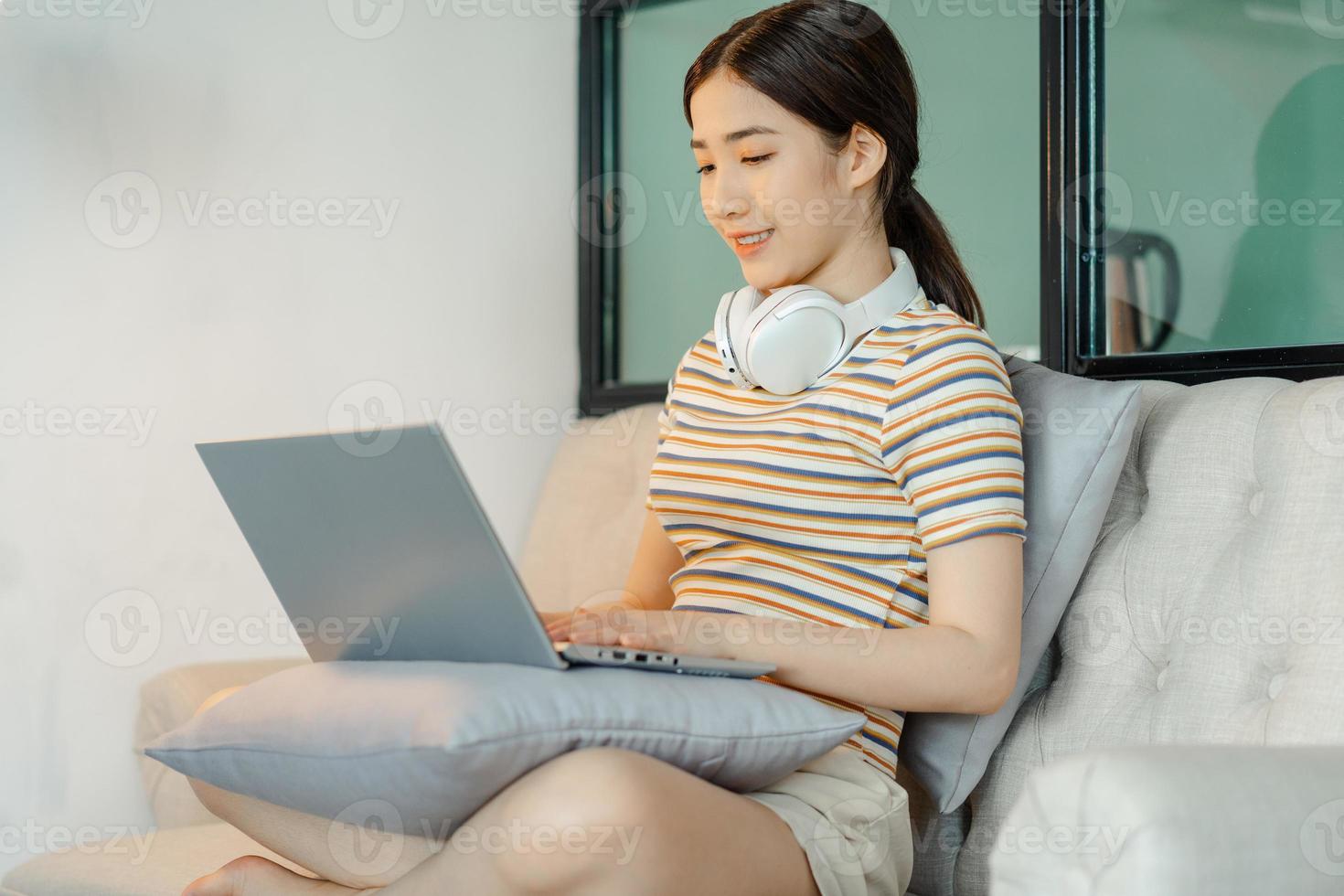 Frau sitzt auf dem Sofa mit Computer foto