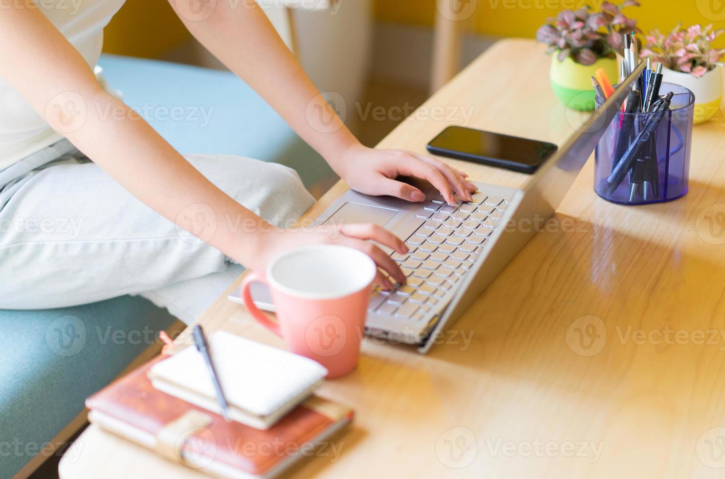 junge Asiatin sitzt auf dem Sofa und arbeitet zu Hause at foto