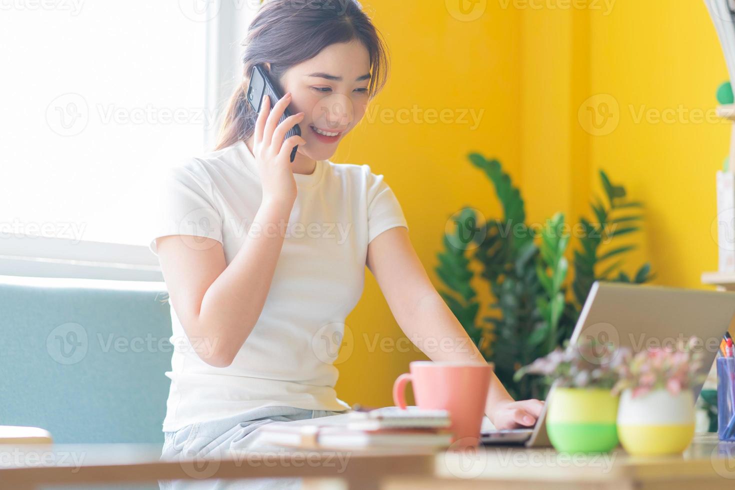 junge Asiatin sitzt auf dem Sofa und arbeitet zu Hause at foto