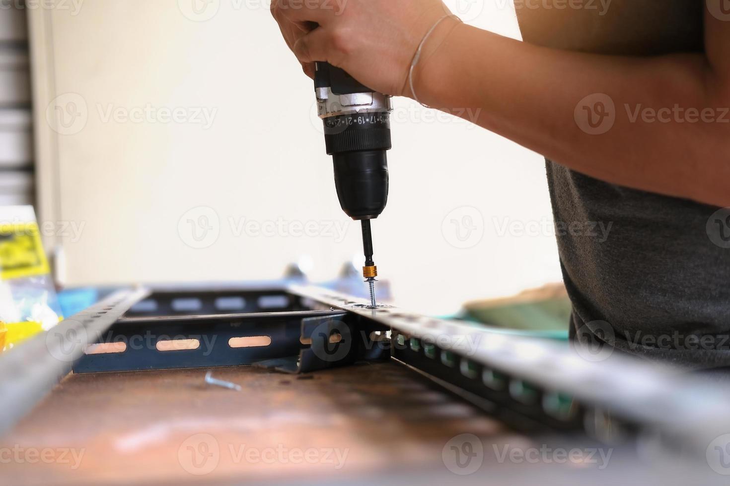 Do-it-yourself-Konzept verwenden Handwerker elektrische Bohrmaschinen, um alte Eisenteile zu montieren. mach ein regal an deinem freien wochenende foto