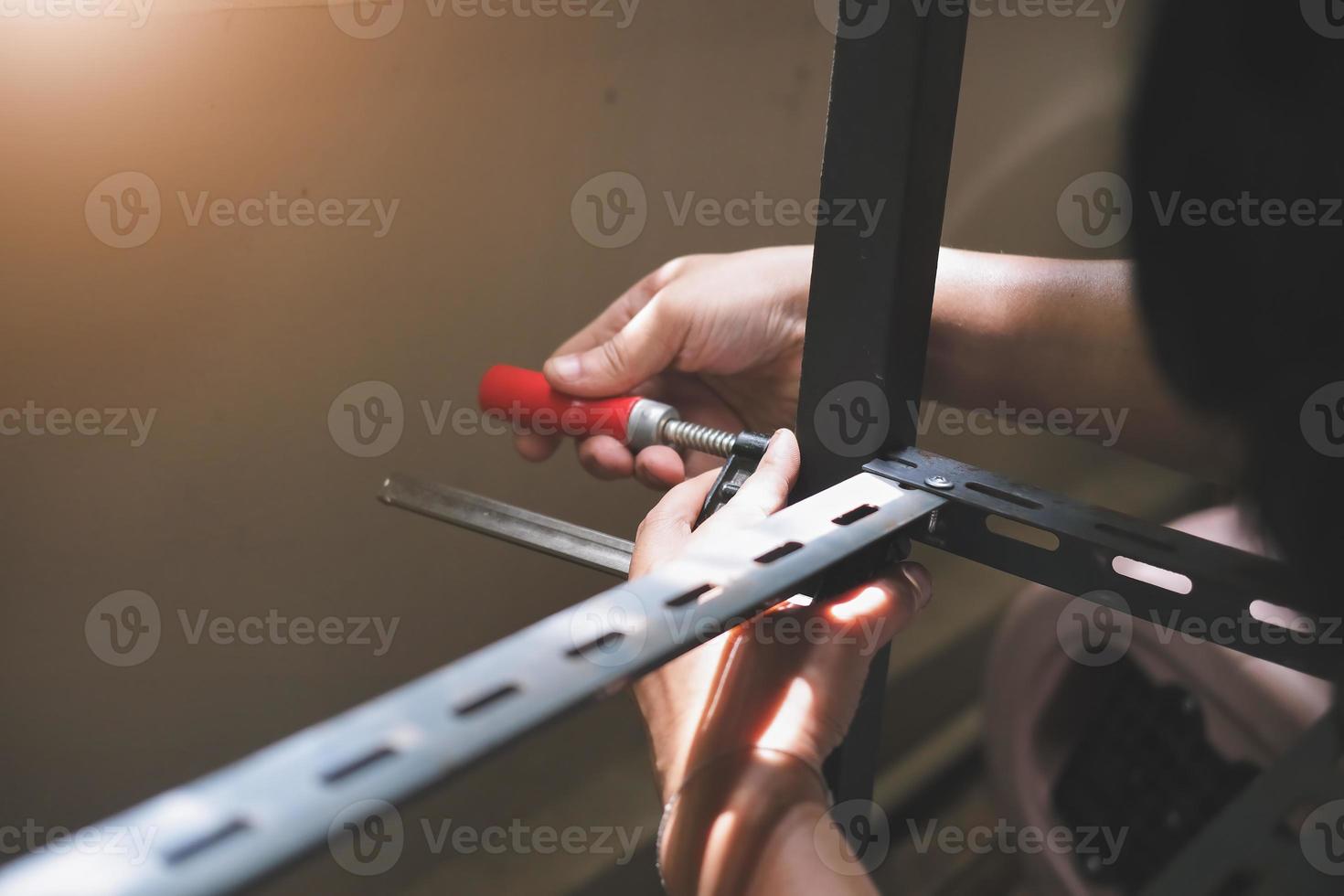 Do-it-yourself-Konzept verwenden Handwerker C-förmige Werkstücke, um alte Eisenteile zu montieren. mach ein Regal an deinem freien Wochenende foto