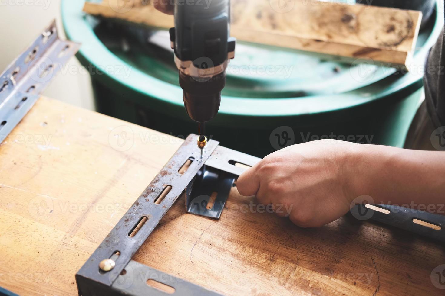 Do-it-yourself-Konzept verwenden Handwerker elektrische Bohrmaschinen, um alte Eisenteile zu montieren. mach ein regal an deinem freien wochenende foto