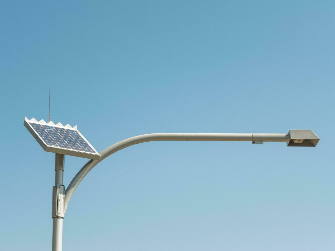 Solar- Zelle Straße Lampe mit lange Arm Stehen gegen Blau Himmel Tag, verwenden das Leistung von das Sonne zu zur Verfügung stellen einfach Beleuchtung Lösungen zum draussen Bereiche. foto