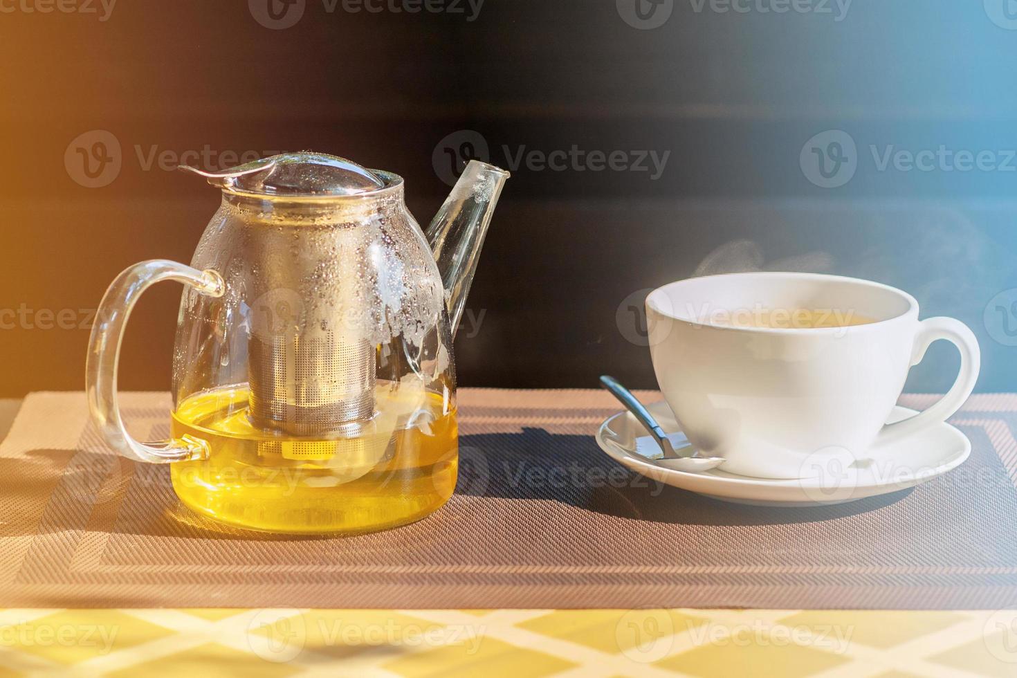 Kräutertee in einer Glasteekanne auf dem Tisch im Freien. grüner Tee in einer Teekanne und einer Tasse. foto