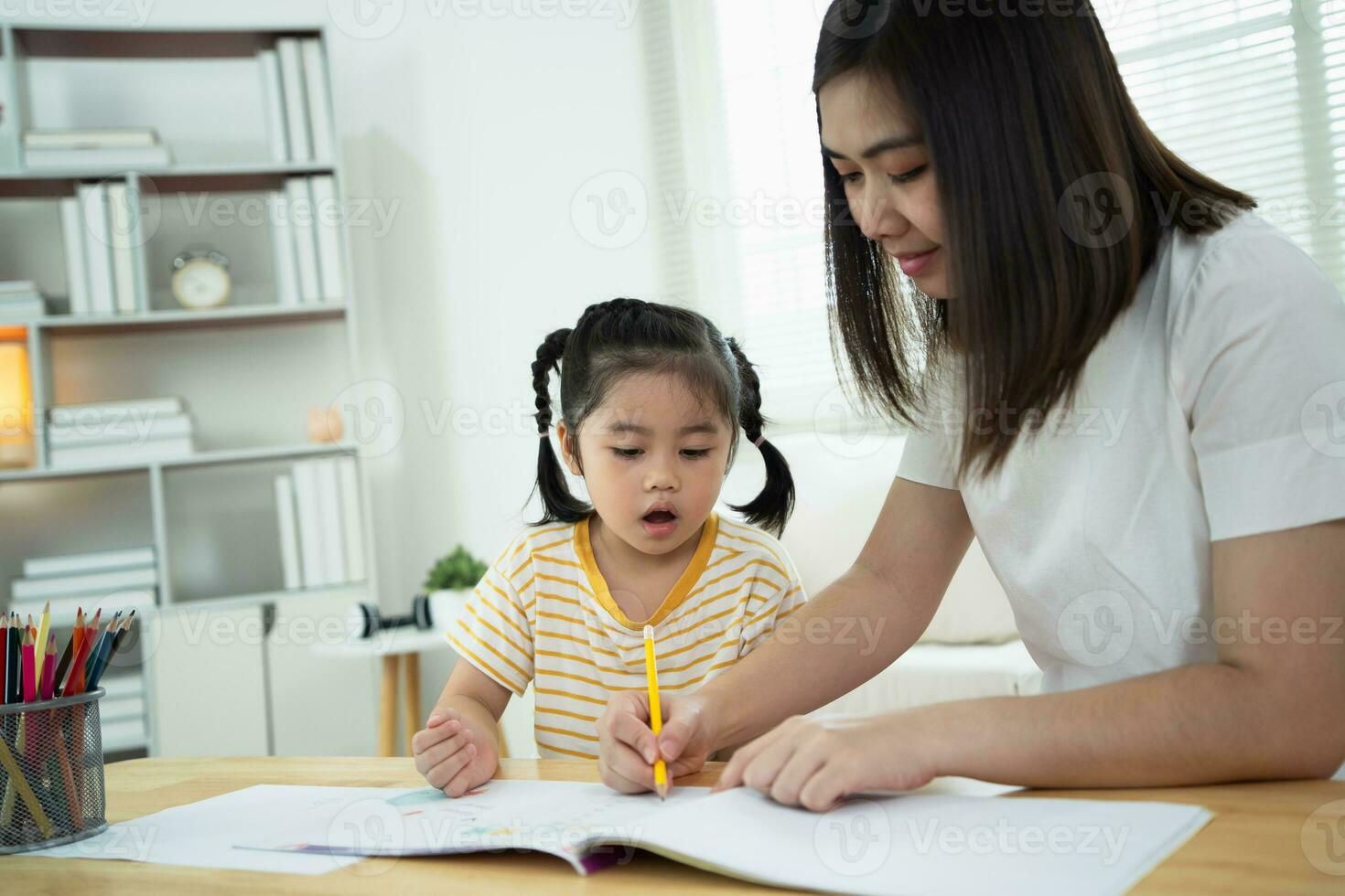 süßes kleines kind, das mit bunten farben malt. asiatische Mädchen und Mutter mit Zeichenstiftfarbe. tochter und mutter machen hausaufgaben zum färben von zeichentrickfiguren. baby-künstler-aktivität-lifestyle-konzept. foto