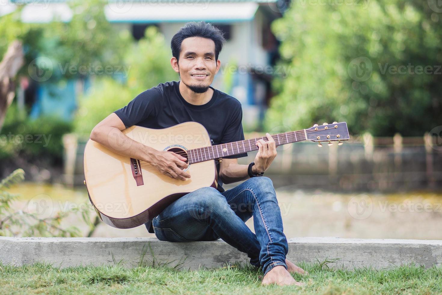 Mann spielt Gitarre im Freien glücklich im Sommer foto