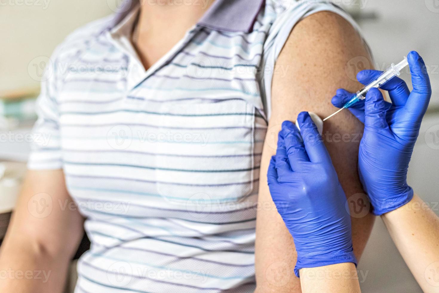 Ein Arzt impft in einer Klinik einen Mann gegen Coronavirus. Nahansicht. das konzept der impfung, immunisierung, prävention gegen covid-19. foto