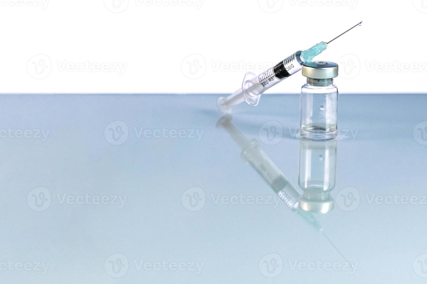 Spritze und Durchstechflasche mit Coronavirus-Impfstoff, Injektionsfläschchendosis auf blauem Hintergrund. Prävention, medizinisches Konzept, Covid-19-Impfung. foto