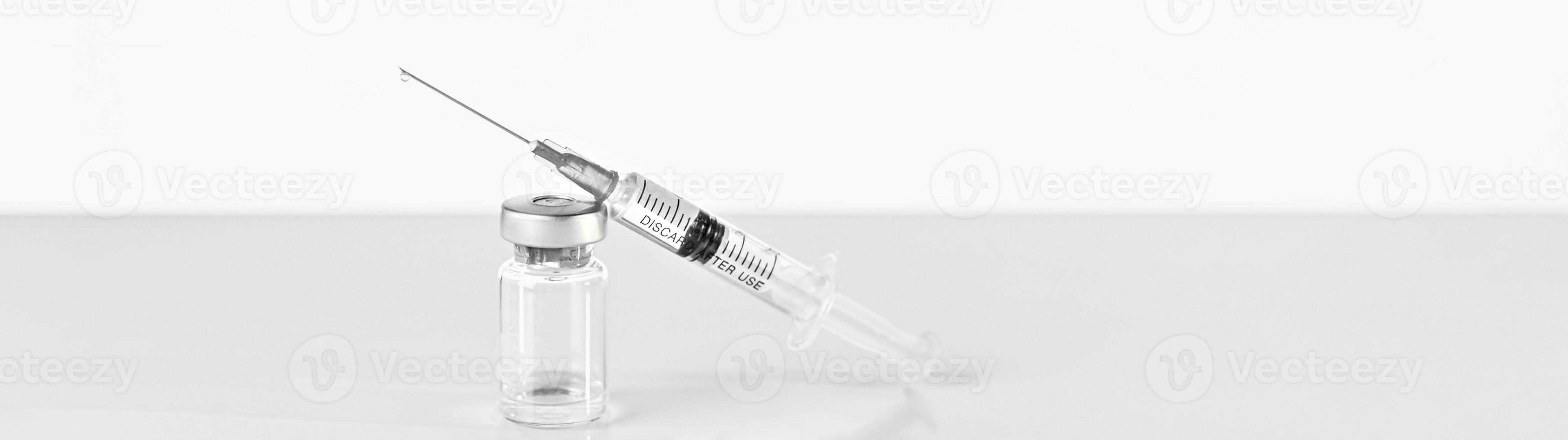 Spritze und Durchstechflasche mit Coronavirus-Impfstoff, Injektionsfläschchendosis auf grauem Hintergrund. Prävention, medizinisches Konzept, Covid-19-Impfung. foto