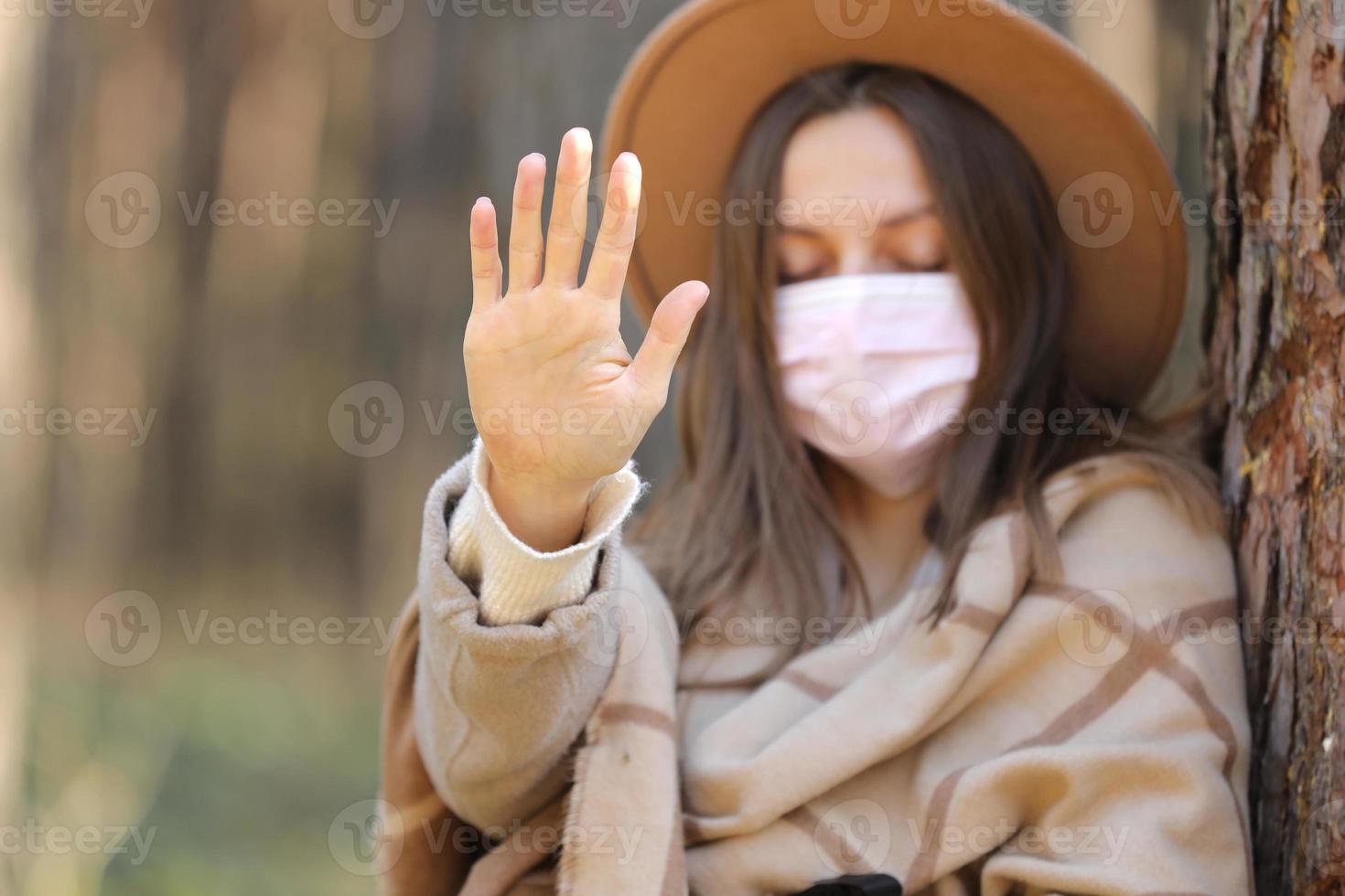 Frau in medizinischer Schutzmaske stoppt Virus draußen im Wald. Luftverschmutzung, Umweltkonzept selektiver Fokus foto