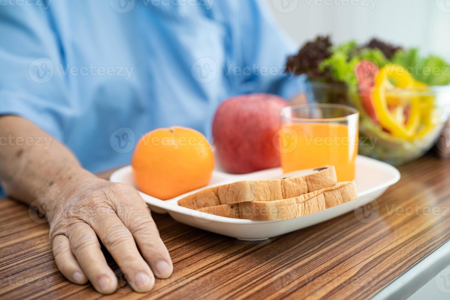 asiatische ältere oder ältere alte Dame Patientin, die gesundes Frühstücksgemüse mit Hoffnung isst und glücklich ist, während sie im Krankenhaus sitzt und hungrig auf dem Bett sitzt foto