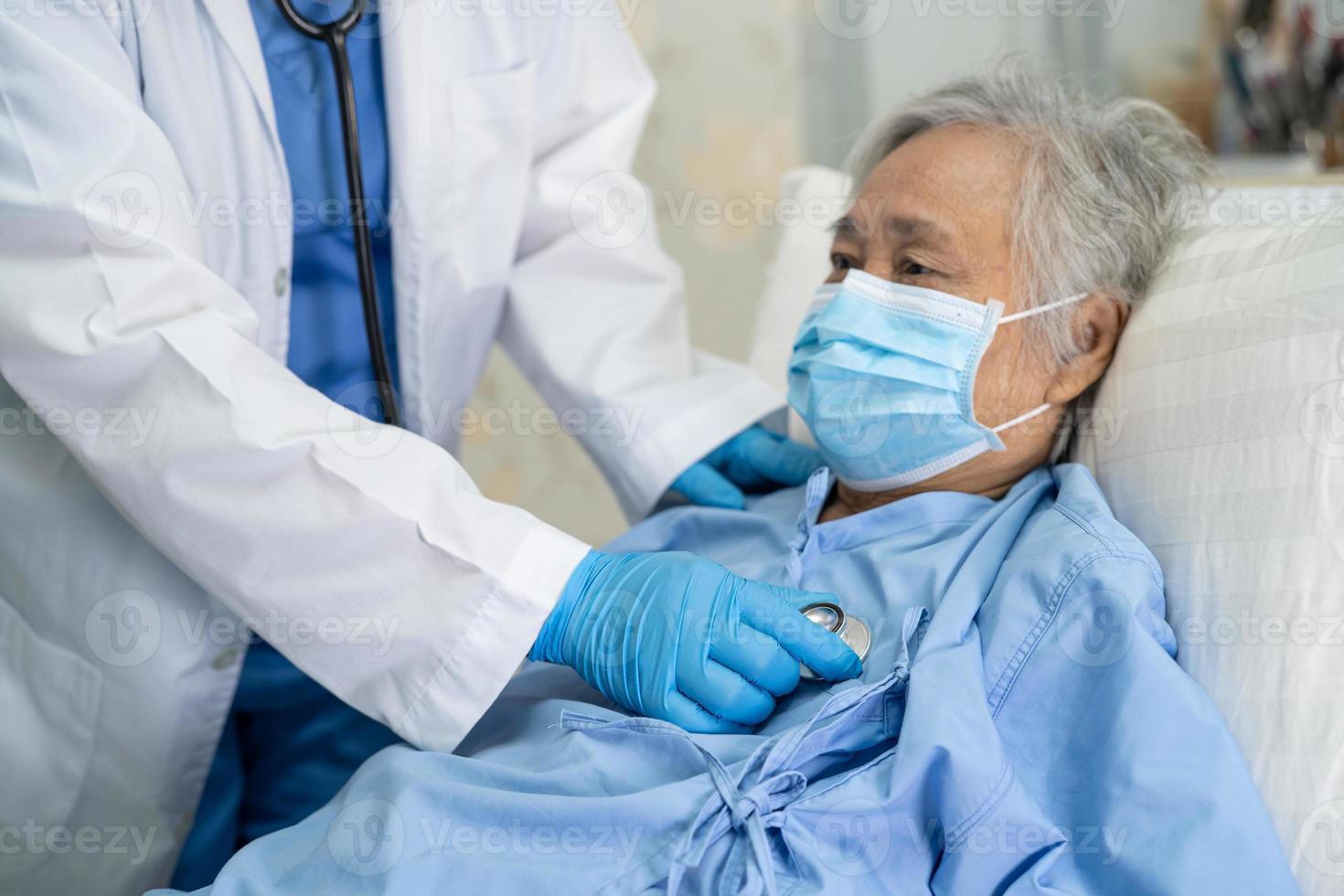 Arzt, der ein Stethoskop verwendet, um asiatische Senioren oder ältere Frauen mit einer Gesichtsmaske im Krankenhaus zu überprüfen, um die Infektion mit dem Covid-19-Coronavirus zu schützen. foto