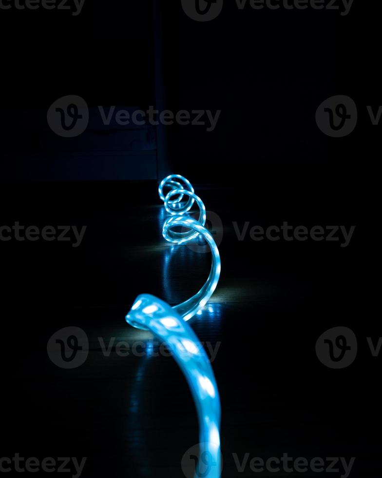 blau leuchtender LED-Streifen mit kaltem Licht auf schwarzem Hintergrund, Nahaufnahme, dekorative Beleuchtung foto