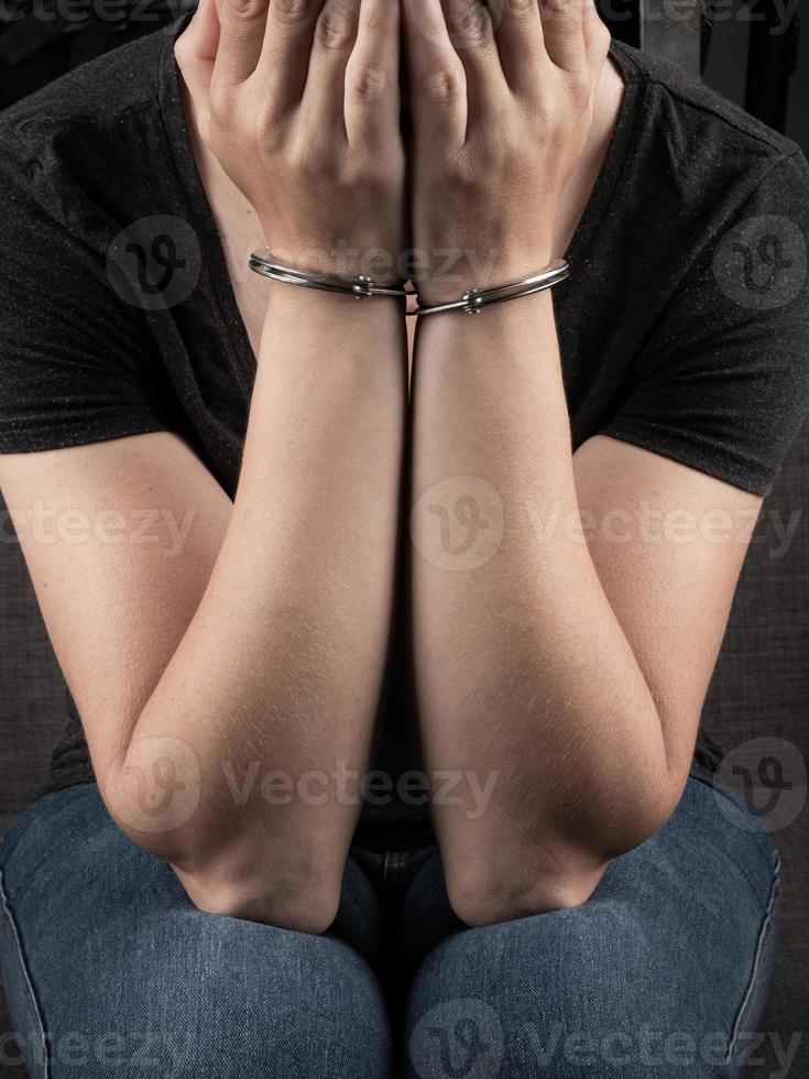 Frau in Handschellen bedeckte ihr Gesicht und bedauert das Verbrechen foto