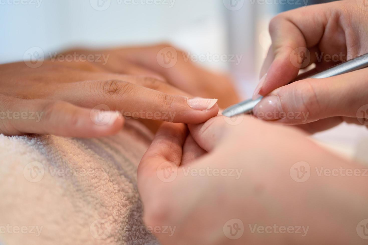 Frau in einem Nagelstudio, die eine Maniküre mit Nagelfeile erhält foto