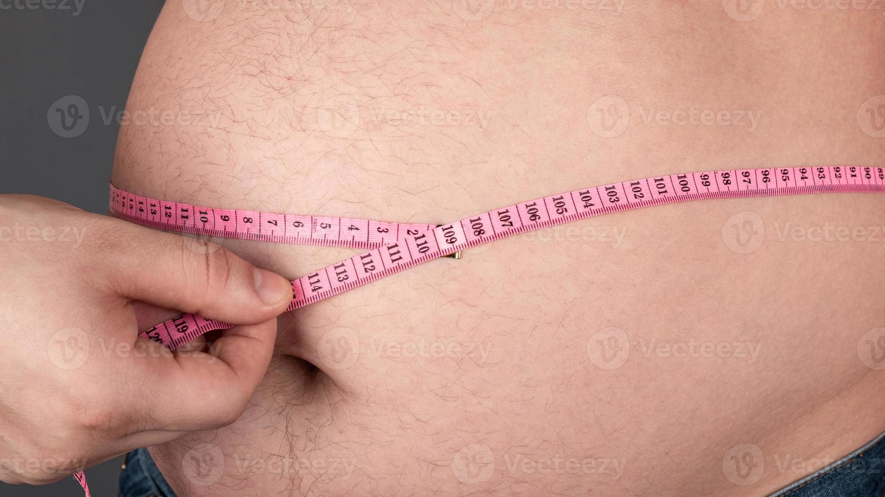 Fettleibigkeitskonzept, messen Sie einen großen fetten Bauch mit einem Zentimeter cent foto