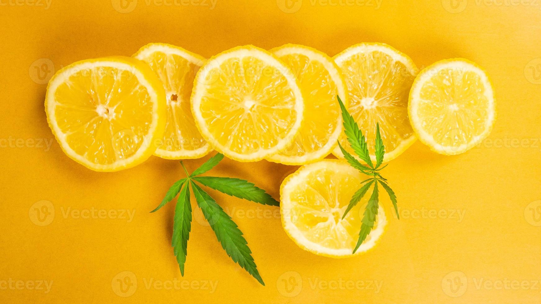 Zitronenscheibe und Marihuanablätter auf gelbem Hintergrund, Cannabis mit Zitrusgeschmack foto