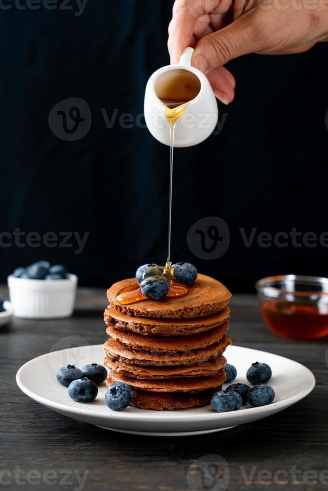 Schokoladenpfannkuchenstapel mit Heidelbeeren und Honig auf einem Teller foto