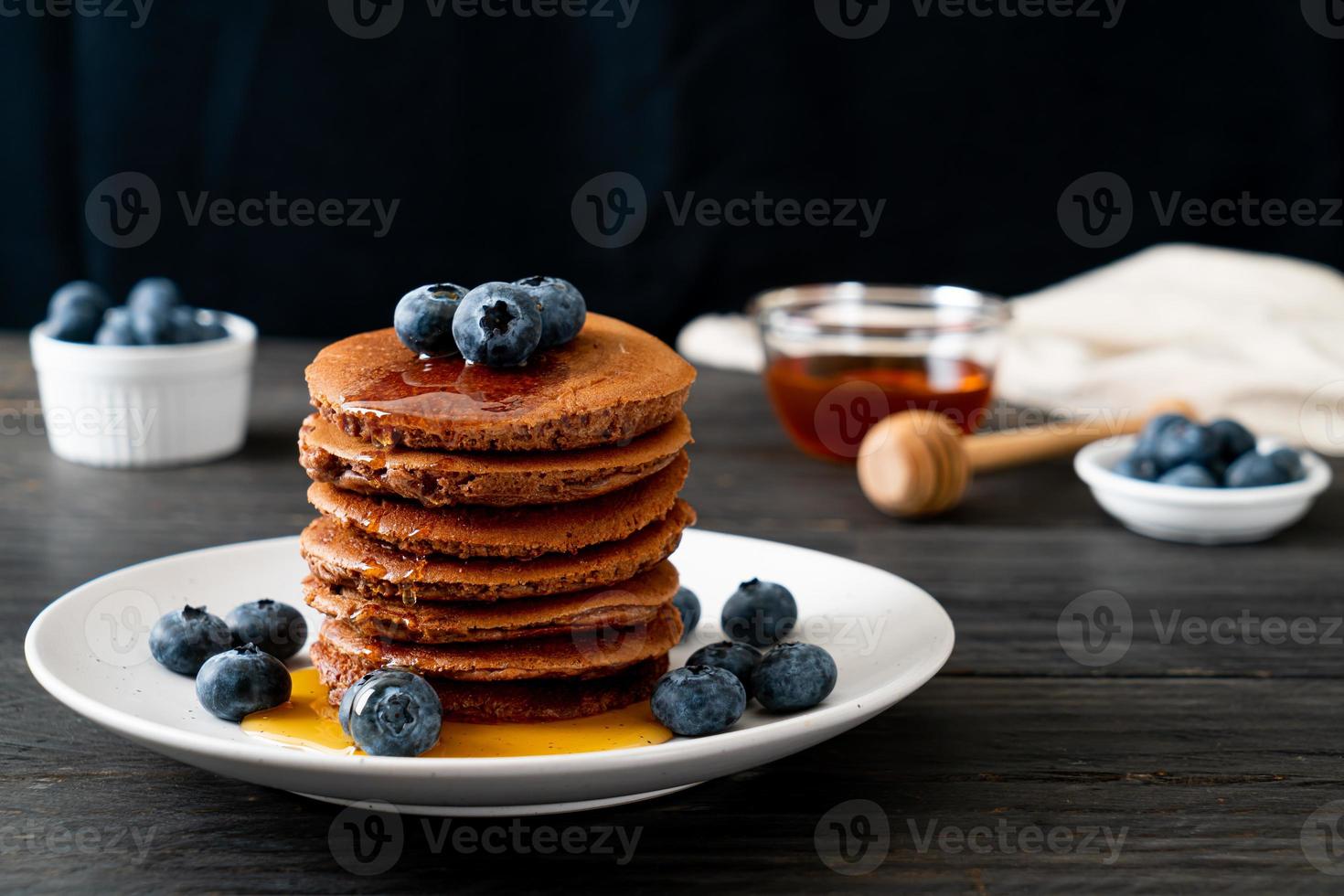 Schokoladenpfannkuchenstapel mit Heidelbeeren und Honig auf einem Teller foto