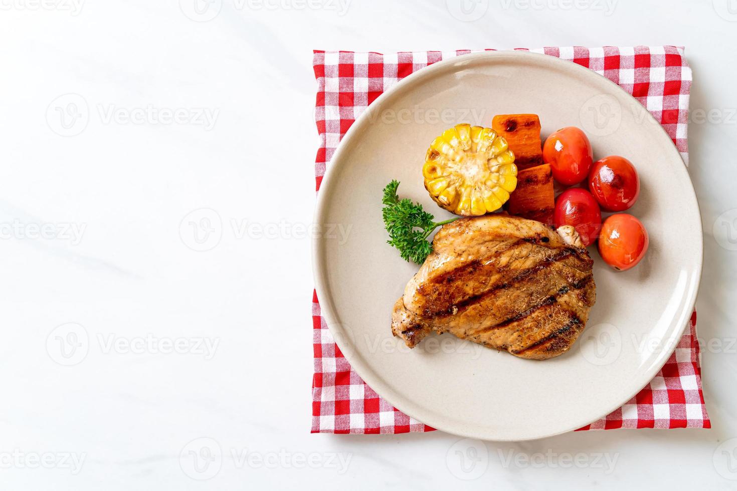 gegrilltes und gegrilltes Schweinefiletsteak mit Mais, Karotte und Tomaten foto