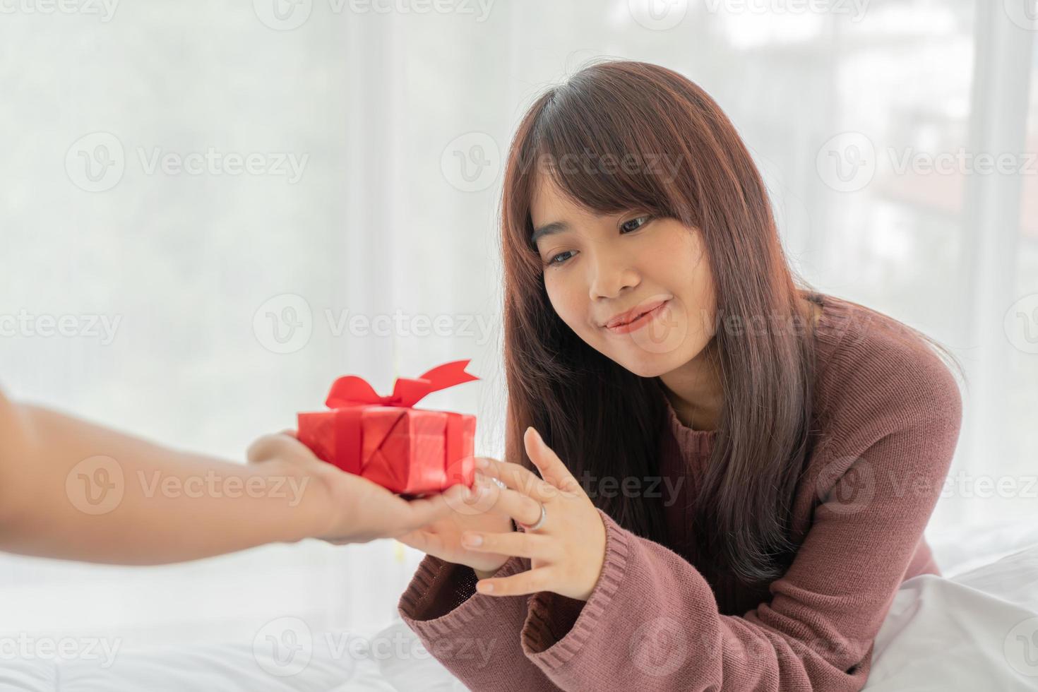 asiatische Frau freut sich über eine Geschenkbox oder ein Geschenk foto