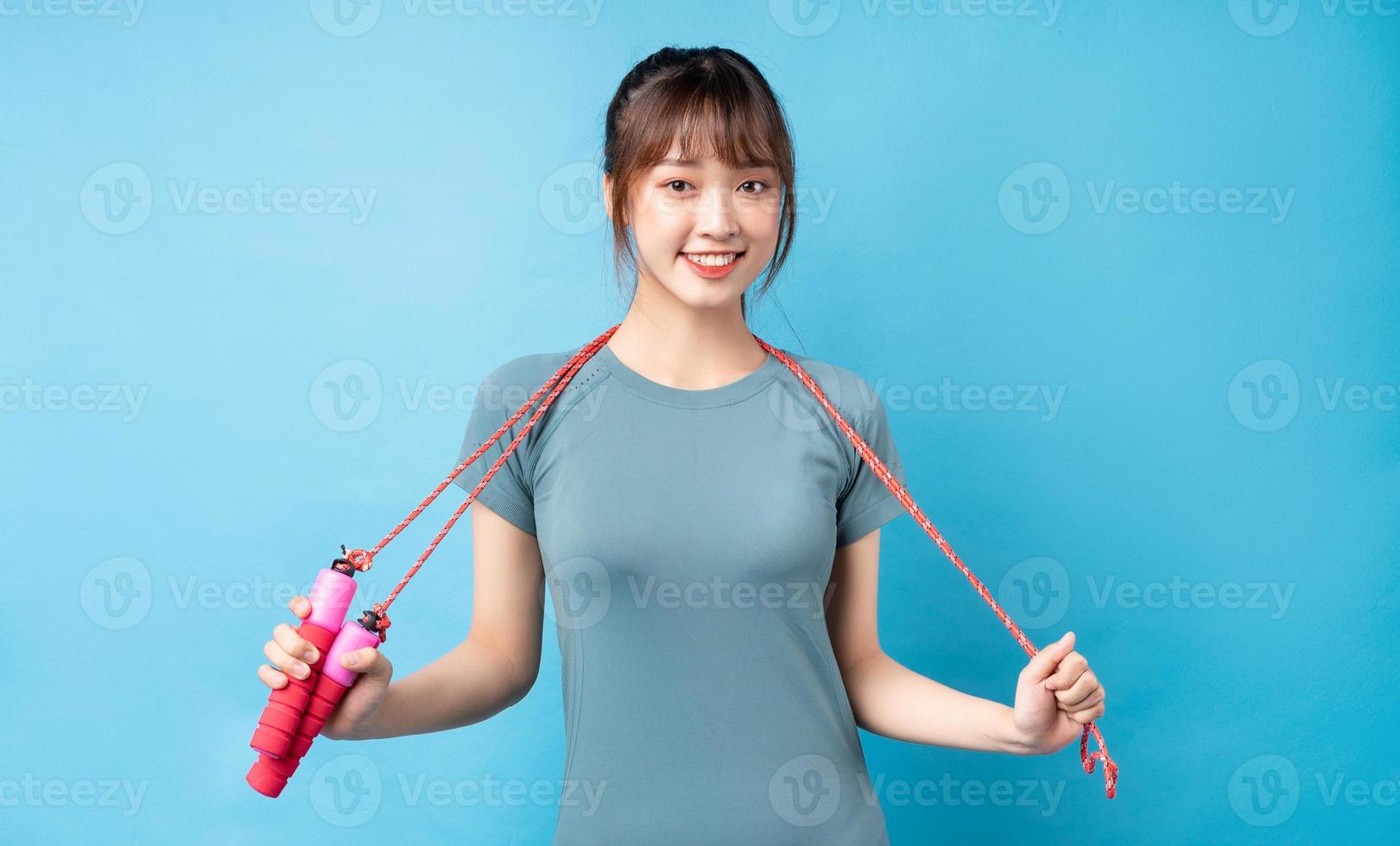 junge asiatische frau, die sportanzug auf blauem hintergrund trägt foto