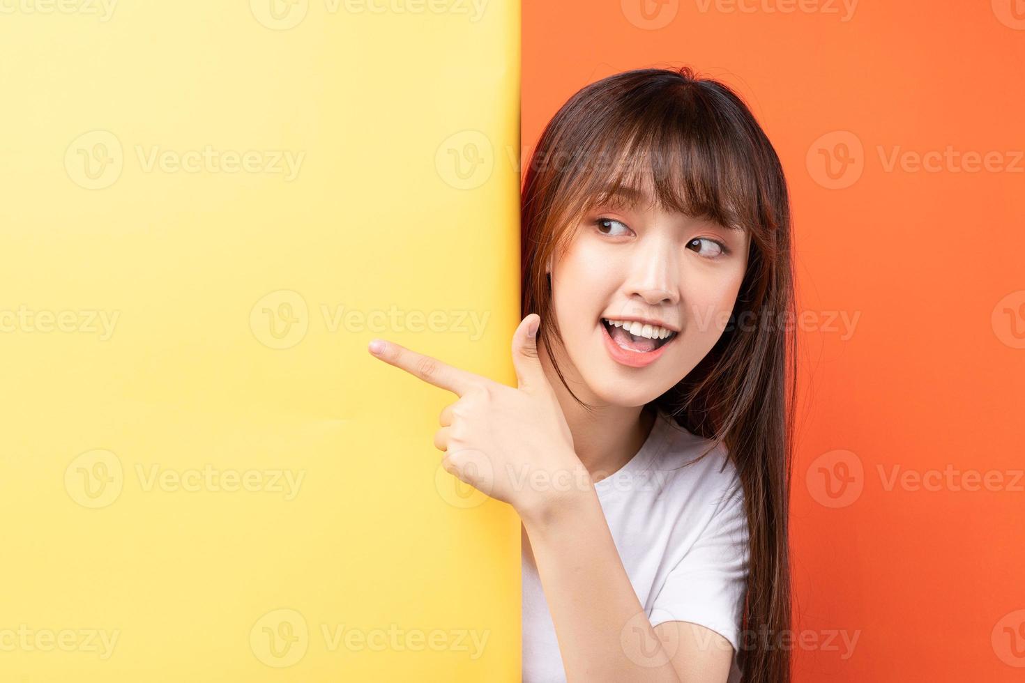 junges asiatisches mädchen, das gelben hintergrund auf orangem hintergrund überlappt foto