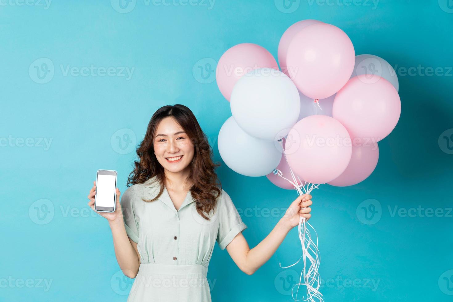 junge asiatische frau, die luftballons hält und telefon benutzt foto