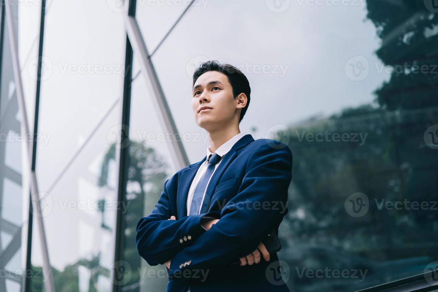 junger asiatischer Geschäftsmann mit modernem Gebäudehintergrund foto