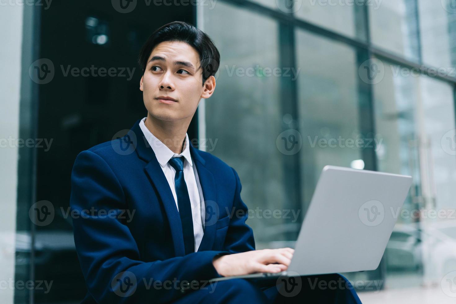 junger asiatischer Geschäftsmann mit modernem Gebäudehintergrund foto