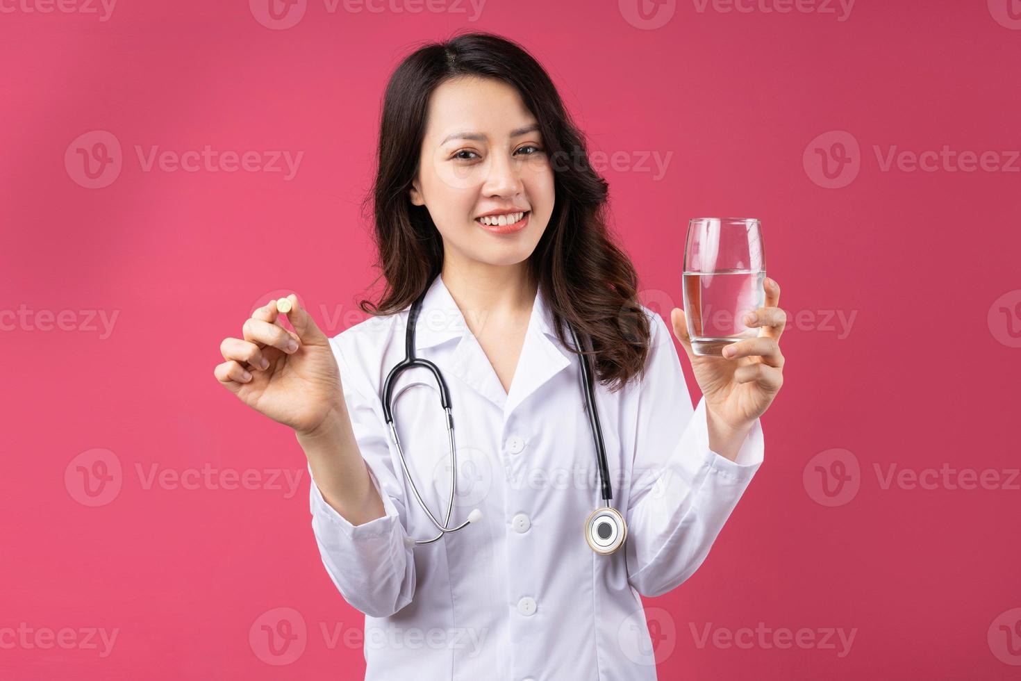 junge asiatische Ärztin mit fröhlichem Ausdruck im Hintergrund foto