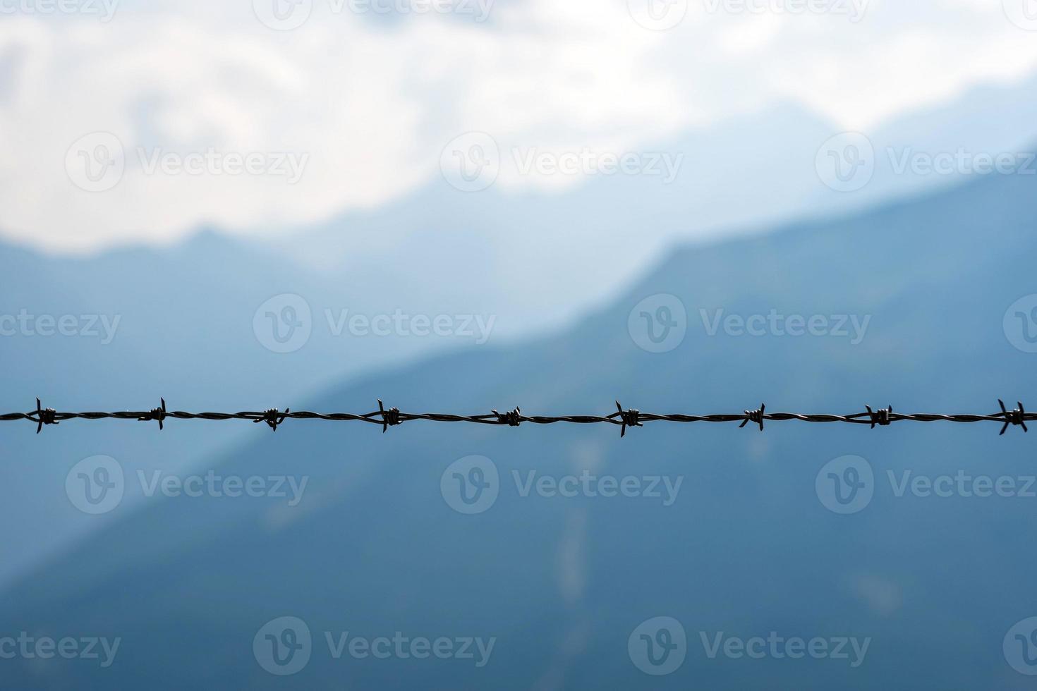 Stacheldraht in Nahaufnahme. der Hintergrund ist eine Berglandschaft. foto