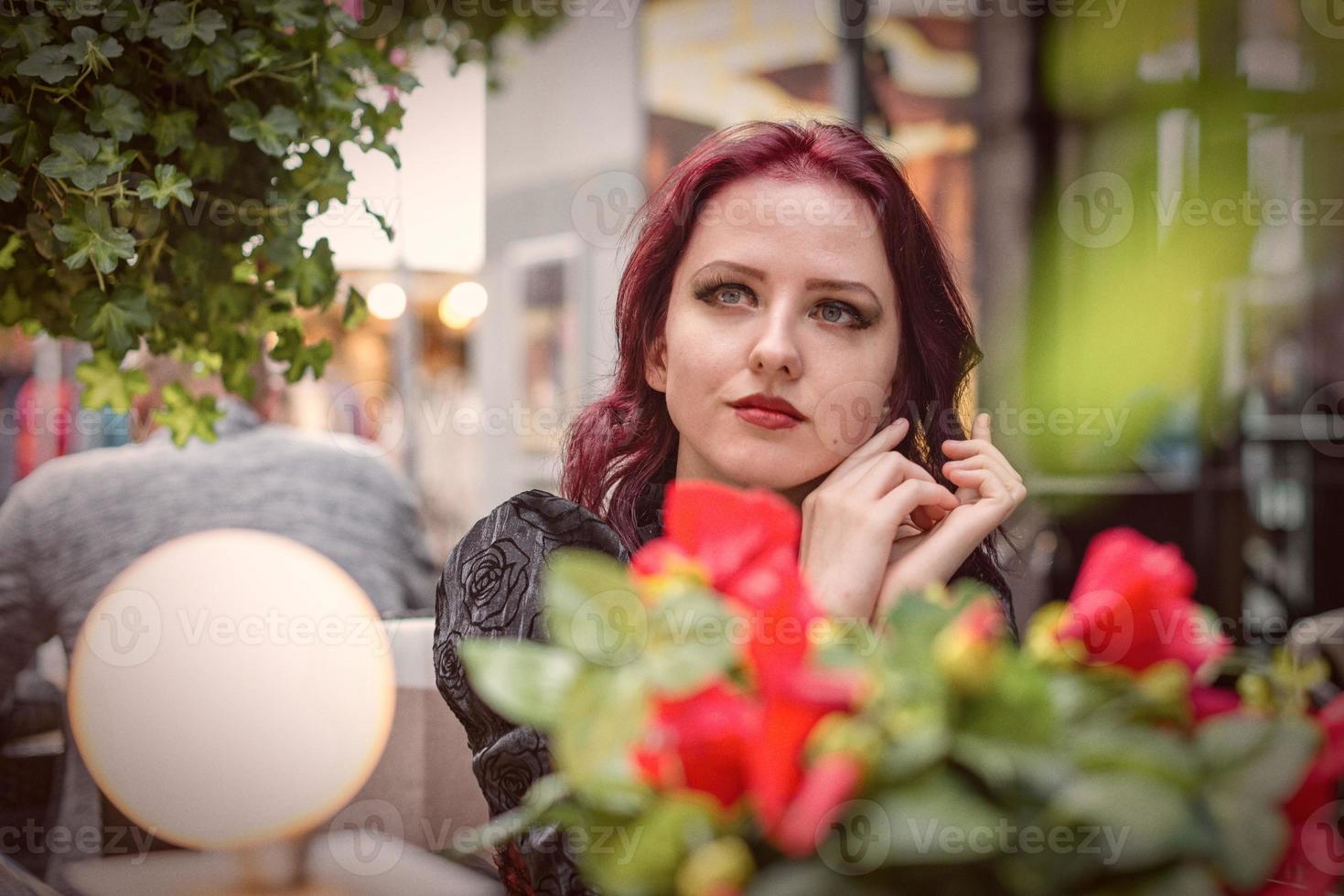 junge wunderschöne rothaarige Frau sitzt in einem Café im Freien, gekleidet in Retro-Mode-Kleidung. foto