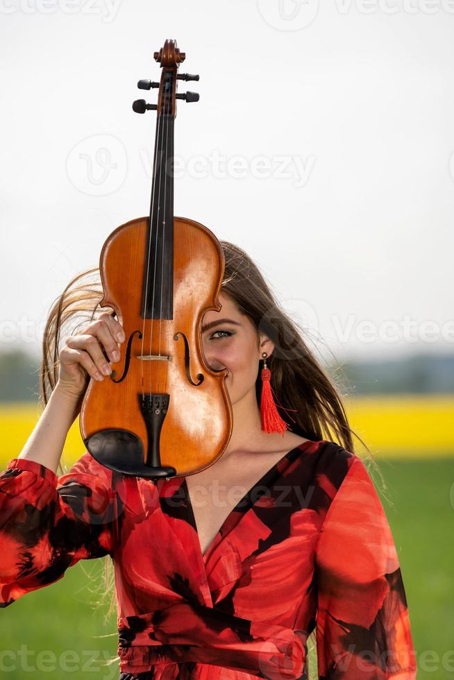 Porträt einer positiven jungen Frau. ein Teil des Gesichts ist vom Geigenhals bedeckt - Bild foto
