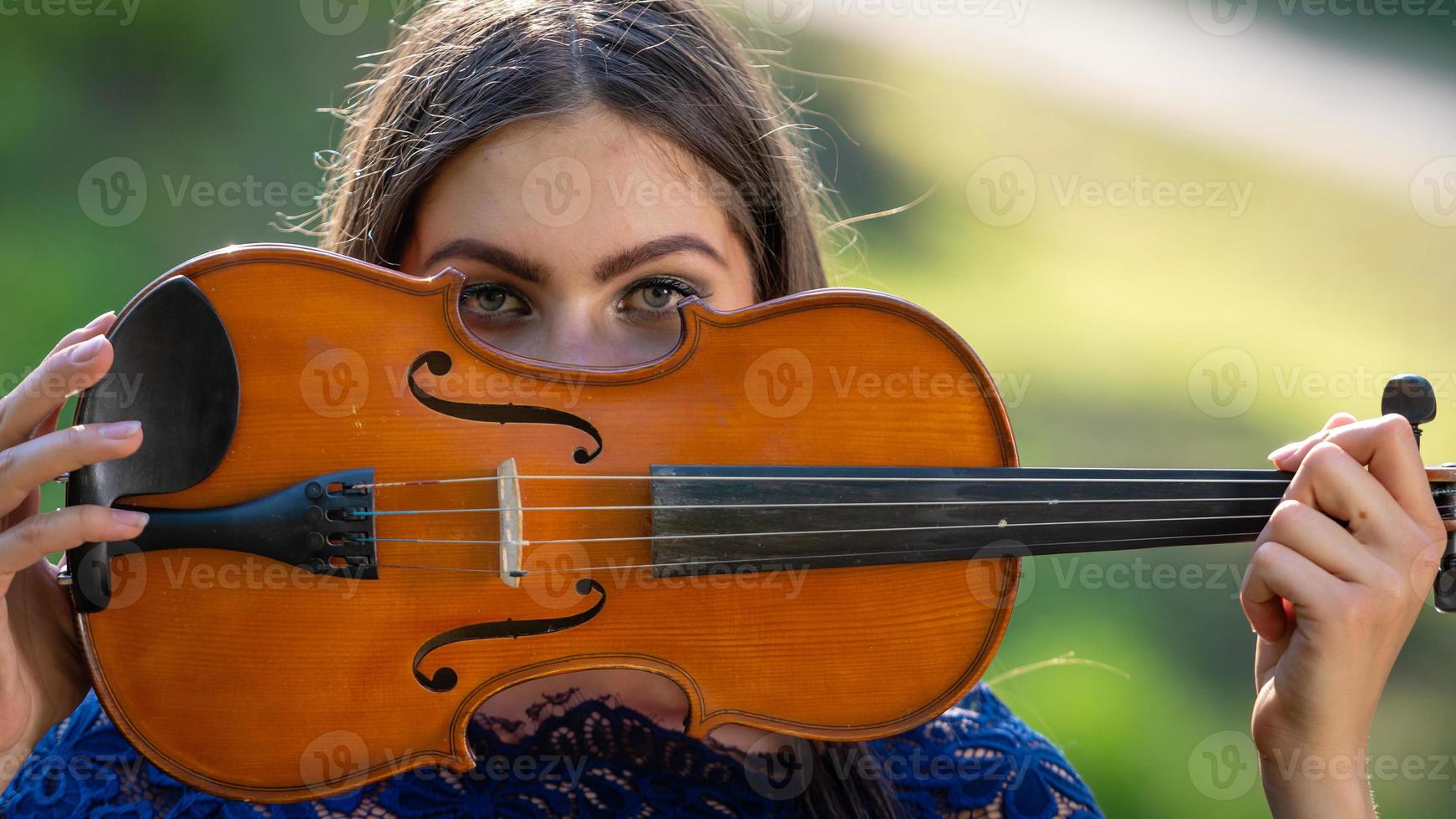 Porträt einer positiven jungen Frau. ein Teil des Gesichts ist vom Geigenhals bedeckt - Bild foto